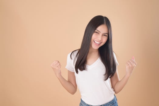 A Portrait of Asian woman with white T-shirt over Light brown background studio photo