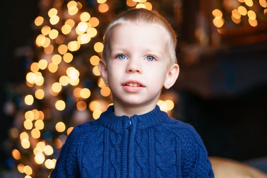 Portrait boy on winter evenings against background christmas lights. Excited photo