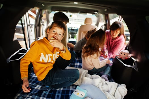 Mother with four kids at vehicle interior. Children in trunk. Traveling by car, lying and having fun, atmosphere concept. photo