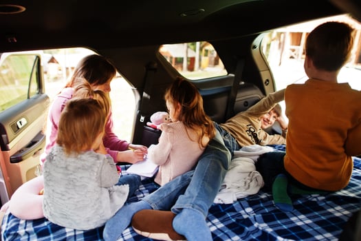 Mother with four kids at vehicle interior. Children in trunk. Traveling by car, lying and having fun, atmosphere concept. photo