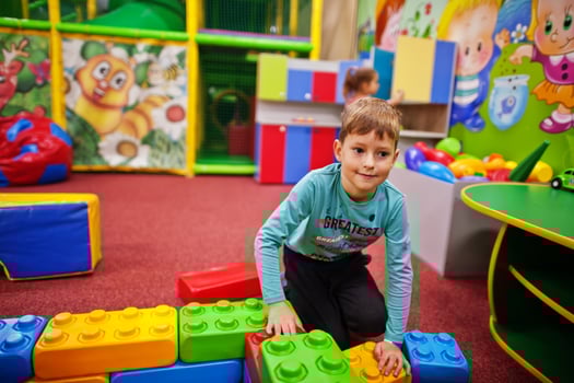 Cute boy playing in indoor play center. Builds with constructor bricks. photo