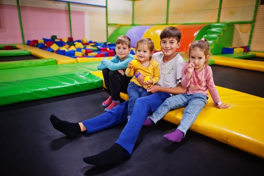 Kids playing in indoor play center and sitting on a trampoline. Large family with four children. photo