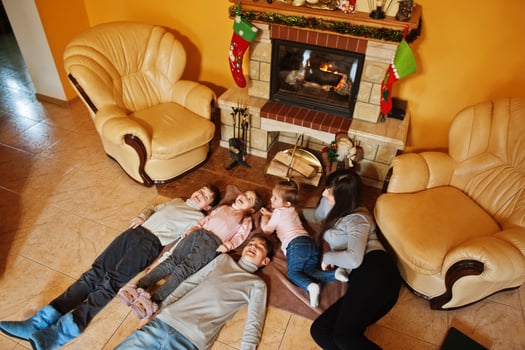 Happy young large family by a fireplace in warm living room on winter day. Mother with four kids at home. photo