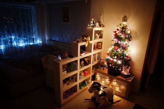 Hobby cow toy against Christmas tree with shining garlands on evening home. photo