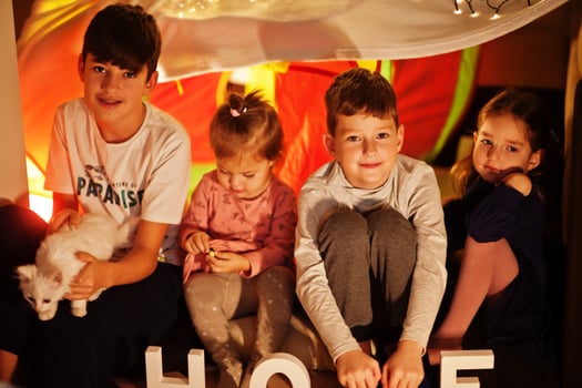 Playing kids with kitty in tent at night home. Hygge mood. photo