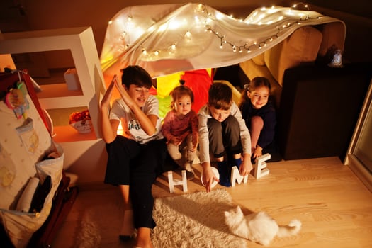 Playing kids with kitty in tent at night home. Hygge mood. photo
