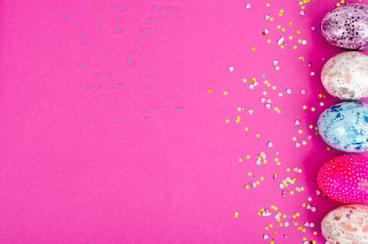 Multicolored handmade easter eggs and confetti on pink background. Minimal concept. View from above. Space for text. Studio Photo