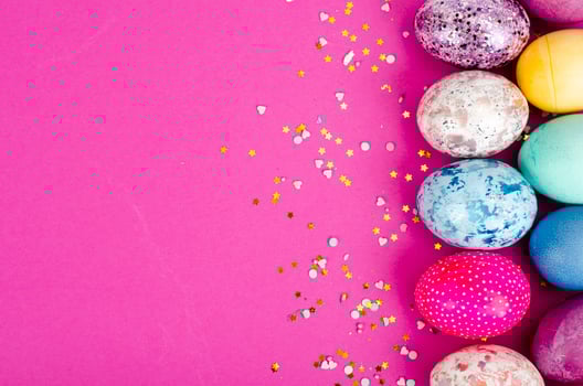 Multicolored handmade easter eggs and confetti on pink background. Minimal concept. View from above. Space for text. Studio Photo