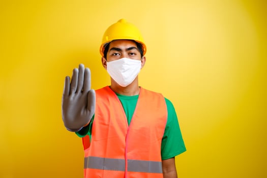 Asian construction worker wearing protective mask making stop gesture photo