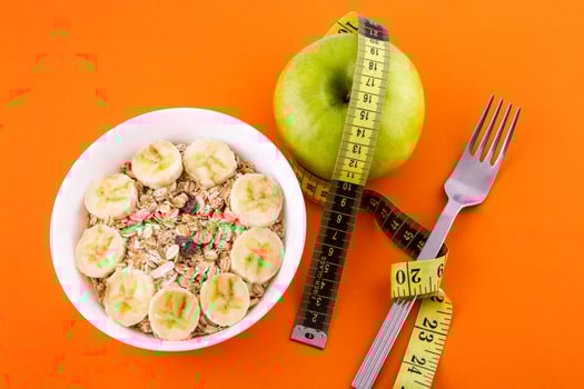 muesli with banana on orange background with apple and measuring tape photo