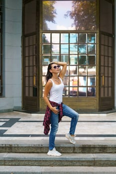 Cute woman in sunglasses poses on the steps in the street near the building photo
