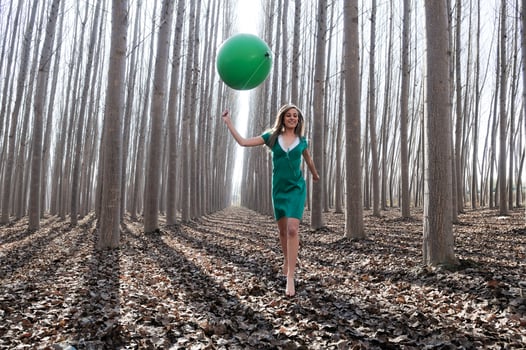 Beautiful blonde girl, dressed in green, walking into the forest photo
