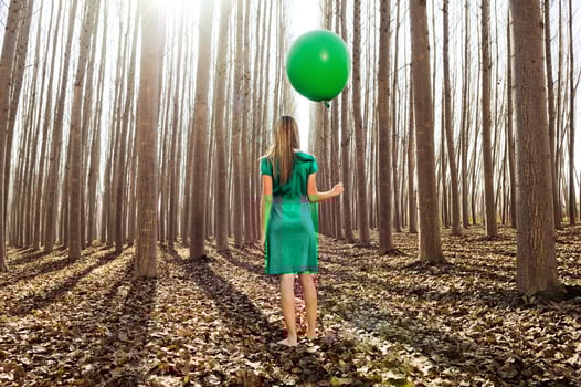 Beautiful blonde girl, dressed in green, standing in the forest photo