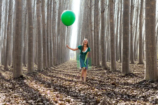 Beautiful blonde girl, dressed in green, laughing in the forest photo