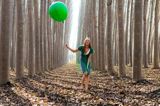 Beautiful blonde girl, dressed in green, laughing in the forest photo
