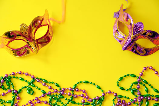 Two multi-colored carnival masks and beads on yellow background. Mardi Gras photo