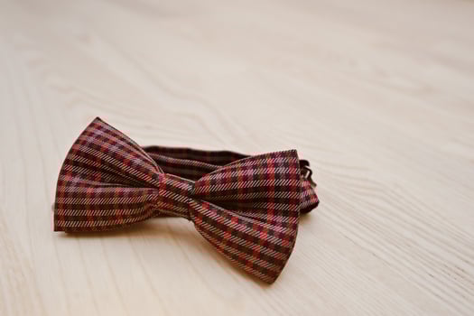 Red checkered bow tie on light wooden background photo