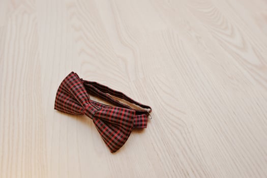 Red checkered bow tie on light wooden background photo