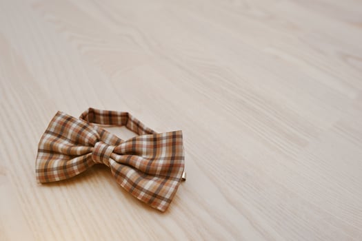 Brown checkered bow tie on light wooden background photo