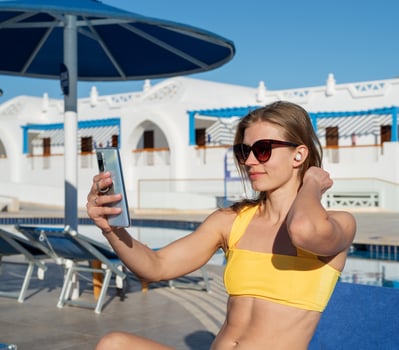 Fit sexy attractive woman sitting by the pool sunbathing taking selfie photo
