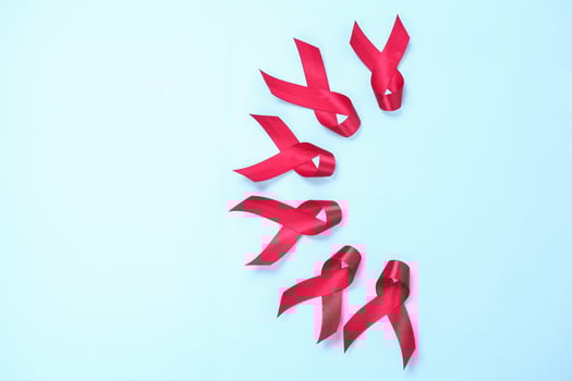red ribbon composed of symbols of AIDS against HIV virus isolated on blue background photo