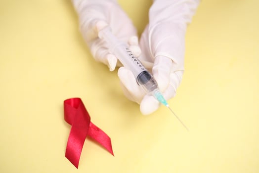 red ribbon with medical gloves and syringe against HIV isolated on yellow background photo