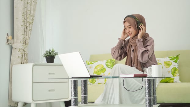 asian woman in hijab working from home while listening intently photo