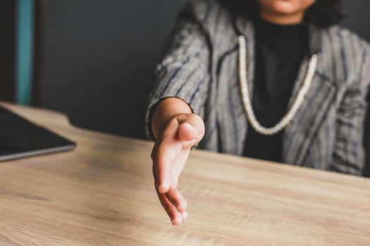 Business woman sitting and gives hand for handshake proposes partnership, successful business, greeting, welcome photo