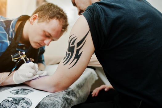 Tattoo master make tattoo for rocker man at tattoo salon photo