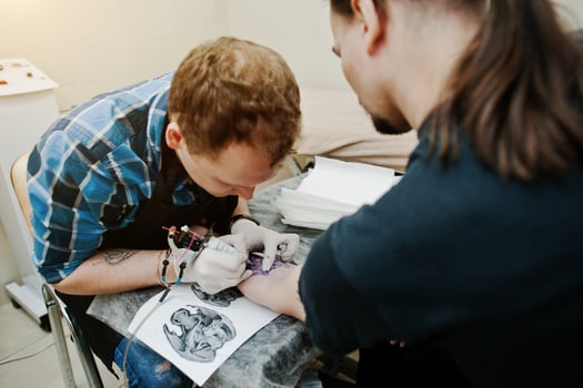 Tattoo master make tattoo for rocker man at tattoo salon photo