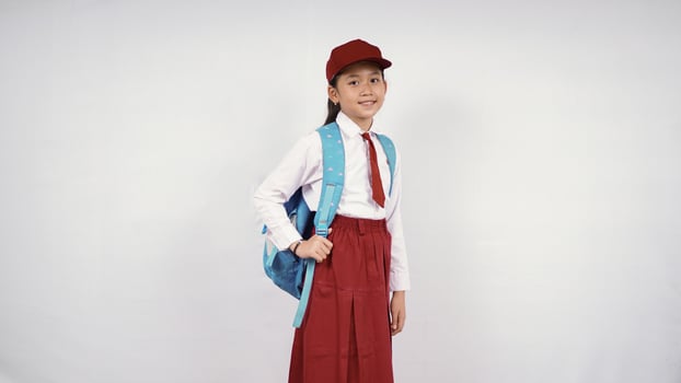 asian little girl wearing hat and school bag smiling happily on white background isolated photo