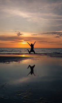 Silhouette of Woman Jumping on Beach at Sunset photo