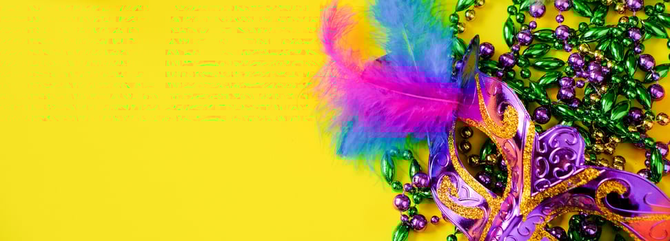 Carnival mask with feathers on yellow background. Multicolored beads Mardi Gras or Fat Tuesday symbol. photo