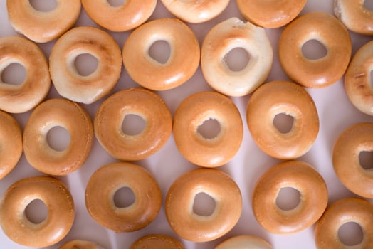 Creative pattern of bagels without sesame seeds on a light background, top view. photo