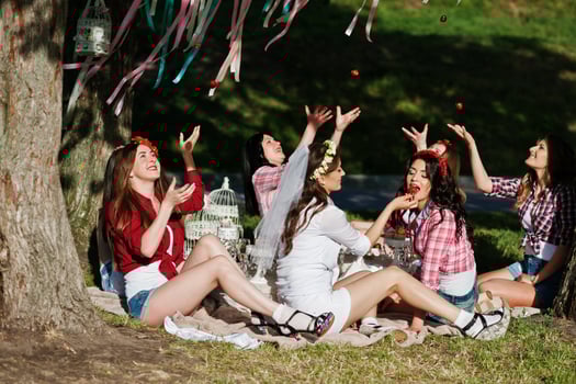 Happy and sexy girls sitting at picnic table and eating strawberries on bachelorette party photo