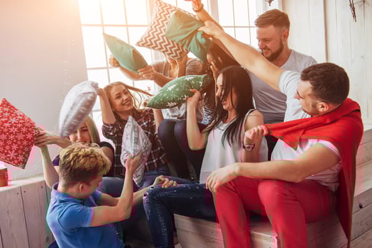 Crazy young best friends fighting pillows at home. Mixed race group of people. Concept  entertainment and lifestyle photo