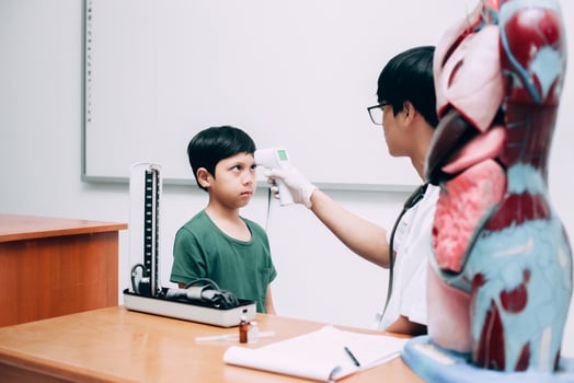 Doctor check boy patient body temperature using infrared forehead thermometer gun photo