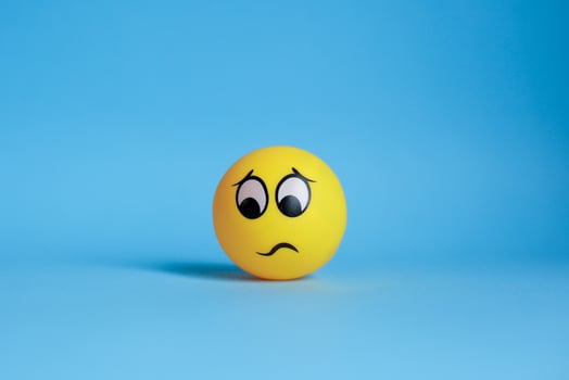 Thinking yellow face with furrowed eyebrows or confused emoticon isolated on blue background photo