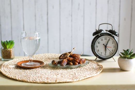 Glass of drinking water and dates with alarm clock showing 6 o'clock. Traditional Ramadan, iftar time concept photo