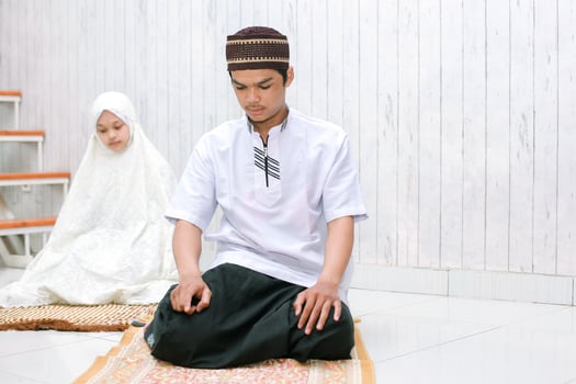Portrait of young couple muslim doing salat together on the prayer mat with last tahiyat photo