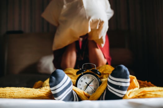 People are awakened from sleep by the alarm clock showing 7 o'clock and cover their ears with pillows photo