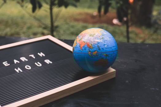 Quote on letter board says Earth hour and earth globe with blurry background photo