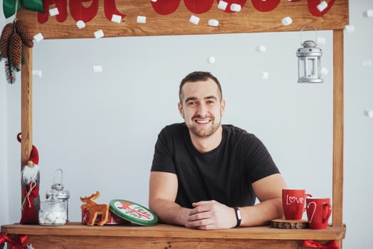 Smiling young man at counter of christmas market photo
