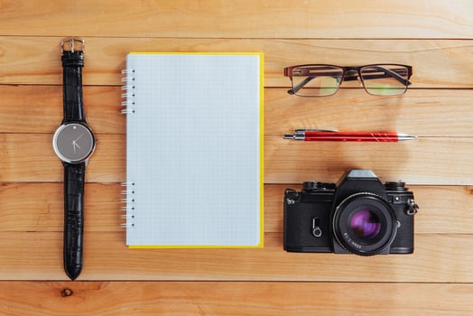 clock, camera and notebook on a brown background photo