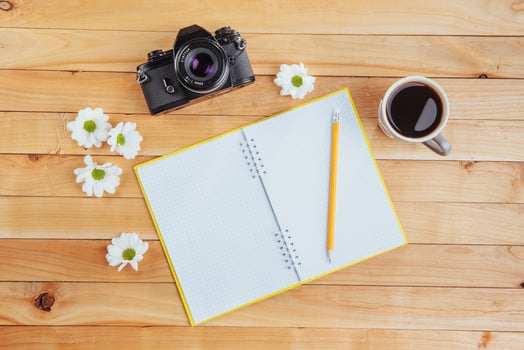 On wooden background notebook pencil, coffee and flowers. photo