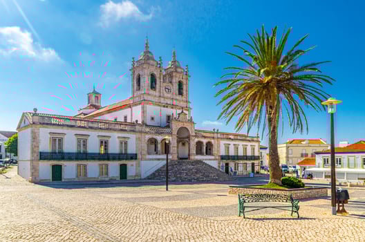 Sanctuary of Our Lady of Nazare catholic church in cobblestone square with palm trees in Sitio hilltop da Nazare town photo