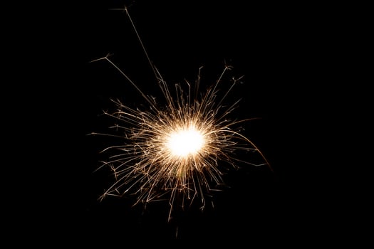 Burning sparkler isolated on black background. Fireworks theme. Light effect and texture. photo