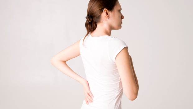 Attractive teenage girl suffers from backache. All on white background photo