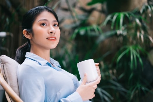Beautiful young Asian woman relaxing in the garden and drinking tea photo