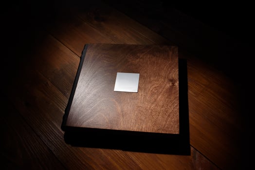 Photo book in a wooden cover on a wooden table. Hard light